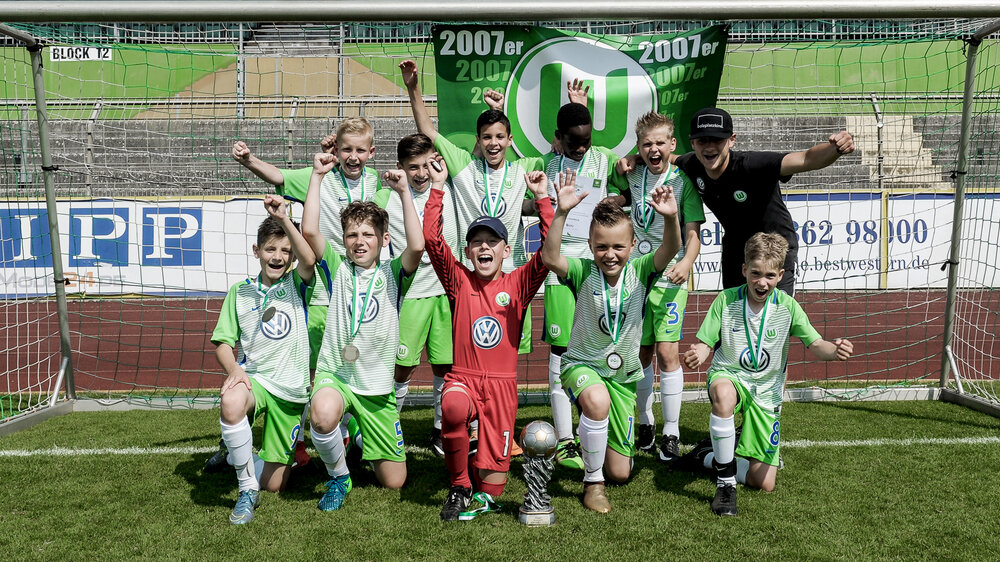 Ein Gruppenbild der E-Jugendmannschaft des VfL Wolfsburg. Die Spieler jubeln in die Kamera. 