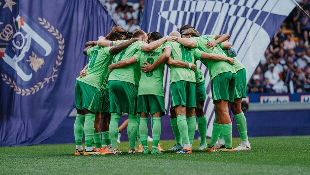 Die Spieler des VfL Wolfsburg bilden einen Kreis.