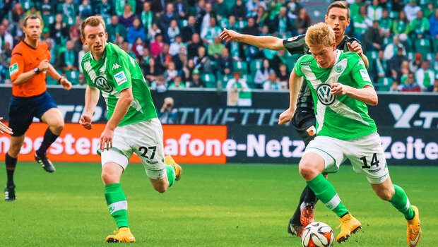 Historisches Foto von den VfL Wolfsburg Spielern de Bruyne und Arnold im Kampf um den Ball mit einem Gegner aus Augsburg.