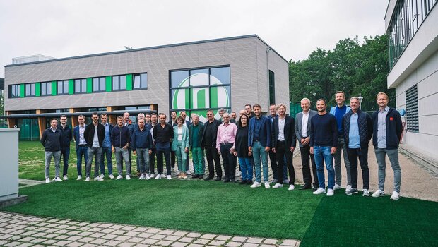 Ein Gruppenbild aller Beteiligten vor dem neuen Funktionsgebäude des VfL Wolfsburg.
