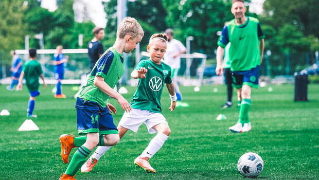 Kleine VfL Wolfsburg Fans spielen beim Familienspieltag vor der Volkswagen Arena gegeneinander Fußball.