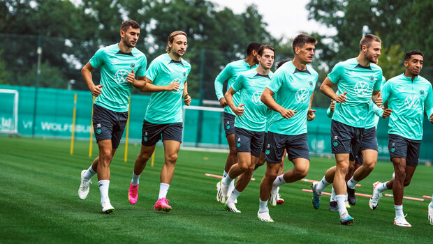 VfL-Wolfsburg-Spieler laufen sich vor dem Training warm.