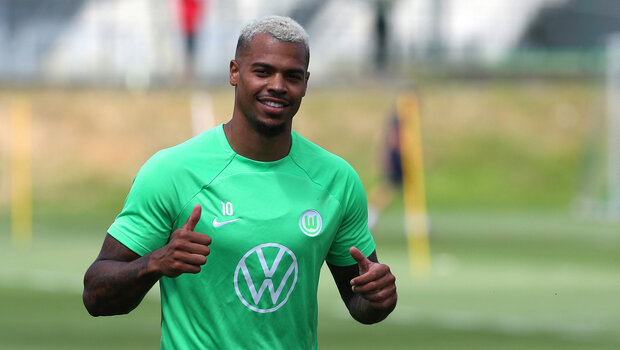 Der VfL Wolfsburg-Spieler Lukas Nmecha zeigt lachend den Daumen nach oben.