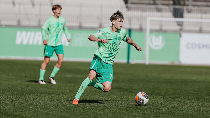 Ein U19 Spieler des VfL Wolfsburg läuft mit dem Ball am Fuß über das Spielfeld.
