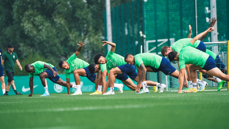 Die Spieler vom VfL Wolfsburg machen Dehnübungen auf dem Trainingsplatz.