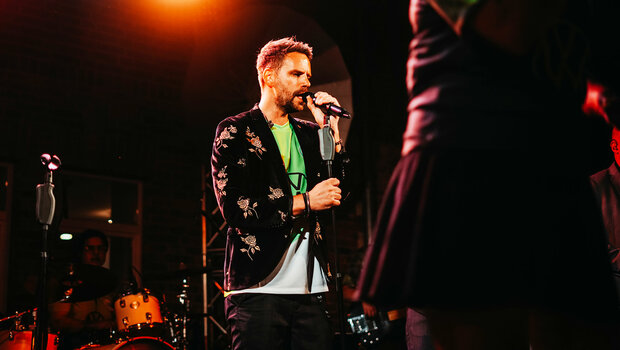 Der Sänger hält das Mikrofon in den Händen und singt auf dem Sommerfest des VfL Wolfsburg.