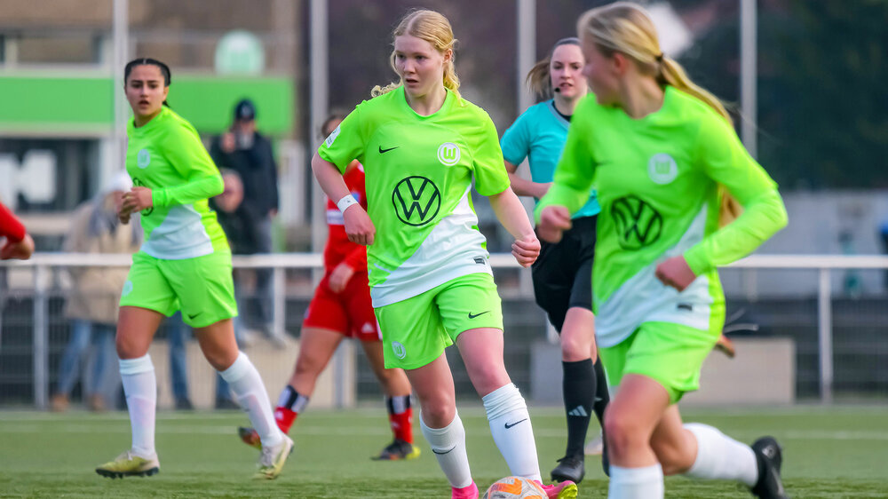 Eine Spielerin der U17 des VfL Wolfsburg am Ball während einem Spiel. Zwei Mitspielerinnen laufen mit.