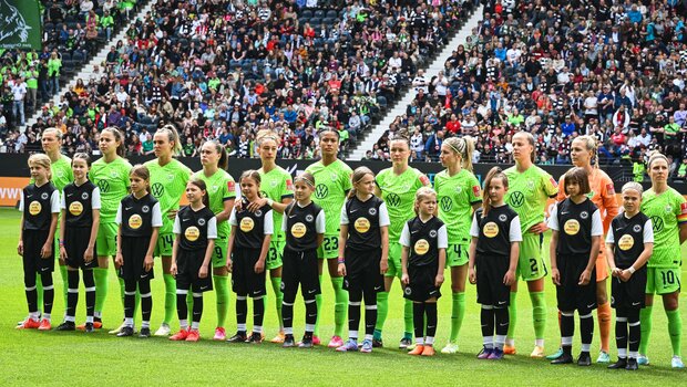 Die Spielerinnen der VfL Wolfsburg Startelf stehen mit Einlaufkindern auf dem Spielfeld