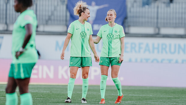 Zwei Spielerinnen vom VfL Wolfsburg stehe nebeneinander auf den Platz.