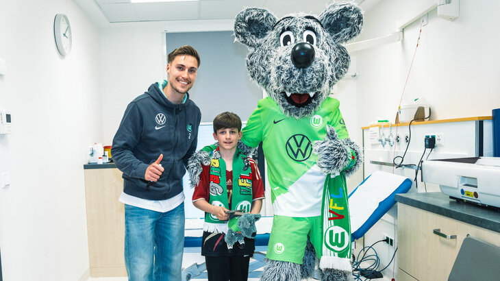 VfL-Wolfsburg-Spieler Kilian Fischer besucht gemeinsam mit Wölfi das Kinderkrankenhaus. Hier macht er ein Foto mit einem kleinen Fan.