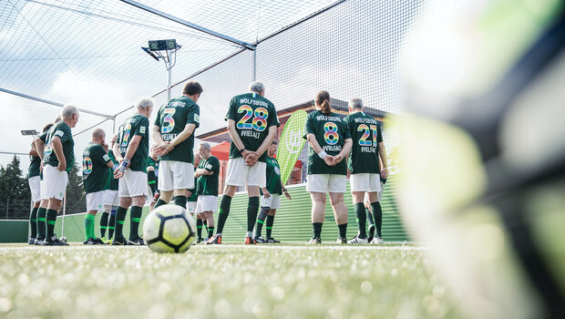 Spieler des VfL-Wolfsburg-Walking-Footballs stehen im Kreis auf dem Fußballplatz.