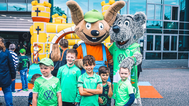 Kleine VfL Wolfsburg Fans posieren beim Familienspieltag an der Volkswagen Arena mit Wölfi.