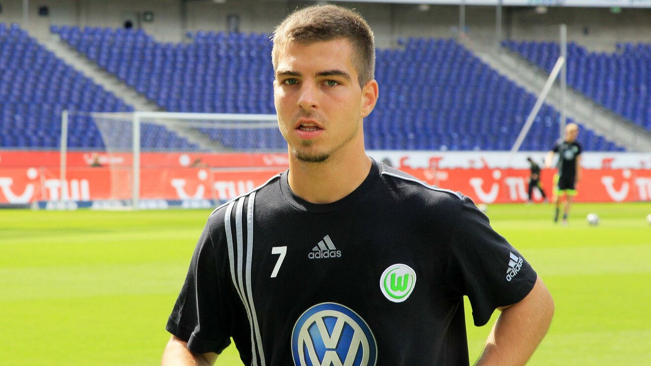 Der ehemalige Spieler des VfL Wolfsburg Kevin Wolze steht auf dem Spielfeld undschaut in die Kamera.