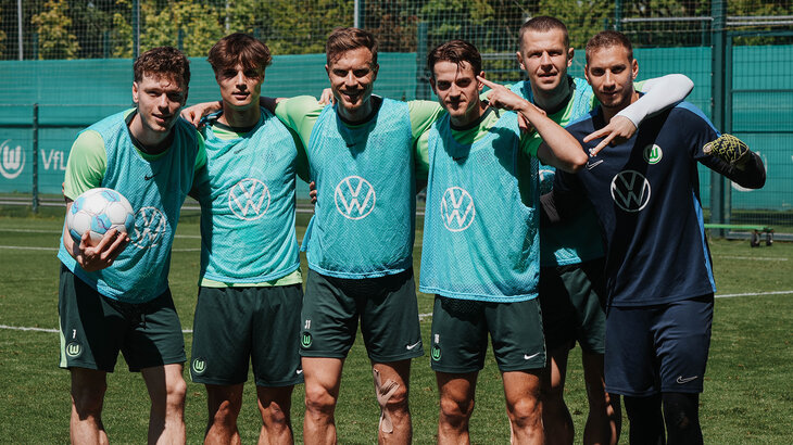Spieler des VfL Wolfsburg umarmen sich und posieren für die Kamera.