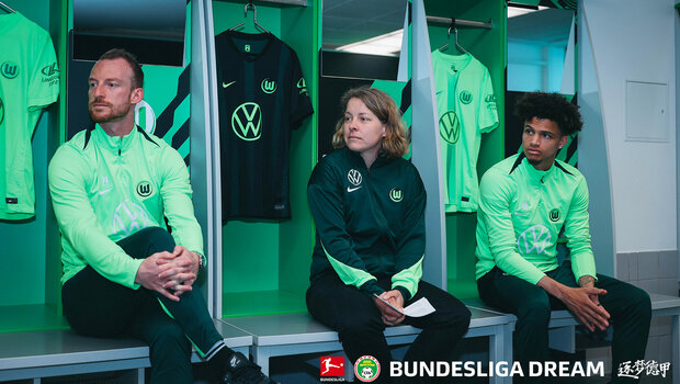 Maximilian Arnold und Kevin Paredes sitzen in der Umkleidekabine und unterhalten sich mit einer Mitarbeiterin.