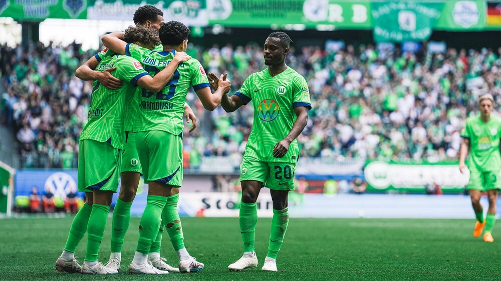 Die Spieler des VfL Wolfsburg stehen jubelnd beisammen.