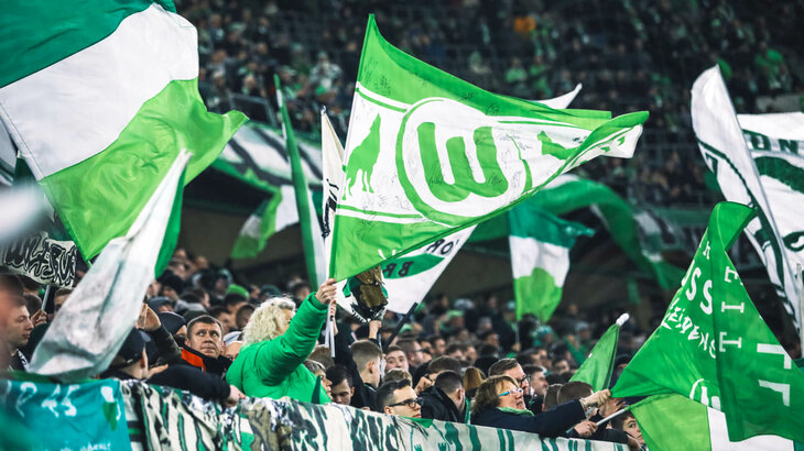 VfL-Wolfsburg-Fans schwenken Fahnen in der Volkswagen Arena.