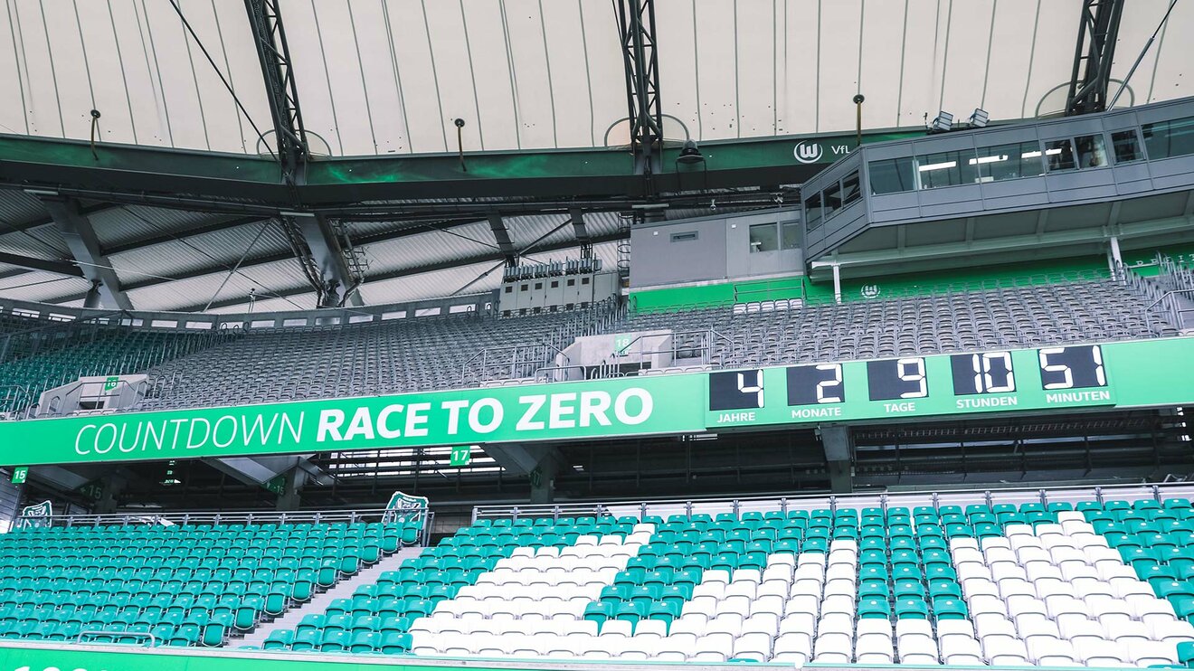 Der Race to Zero Countdown beim VfL Wolfsburg läuft für alle gut sichtbar auf der mittleren Bande des Stadions minutenweise herab.