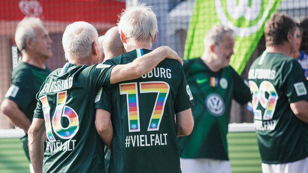 Ein Spieler des VfL-Wolfsburg-Walking-Footballs legt seinem Mitspieler den Arm um die Schultern.