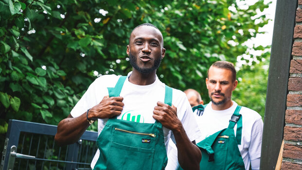 VfL Wolfsburg Spieler Guilavogui trägt eine Malerhose und macht sich motiviert an die Arbeit im Rahmen des "Wir für euch"-Tags.