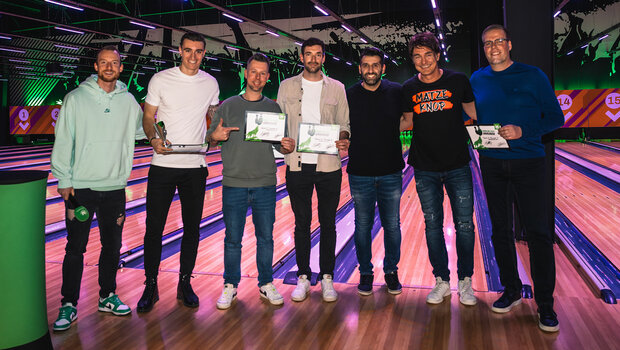 Die Gewinner beim VfL Wolfsburg Bowlingevent für Mitarbeitende halten ihre Urkunden in der Hand.