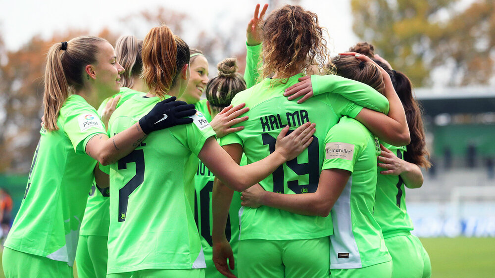 Die VfL Wolfsburg Spielerinnen bejubeln sich umarmend einen Sieg.