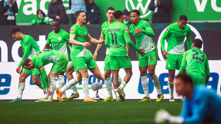 Die Spieler des VfL Wolfsburg stehen jubelnd beisammen. 