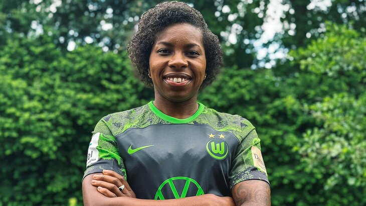 Die neue VfL Wolfsburg Spielerin Lineth Beerensteyn steht im VfL-Trikot mit verschränkten Armen da und lächelt in die Kamera.
