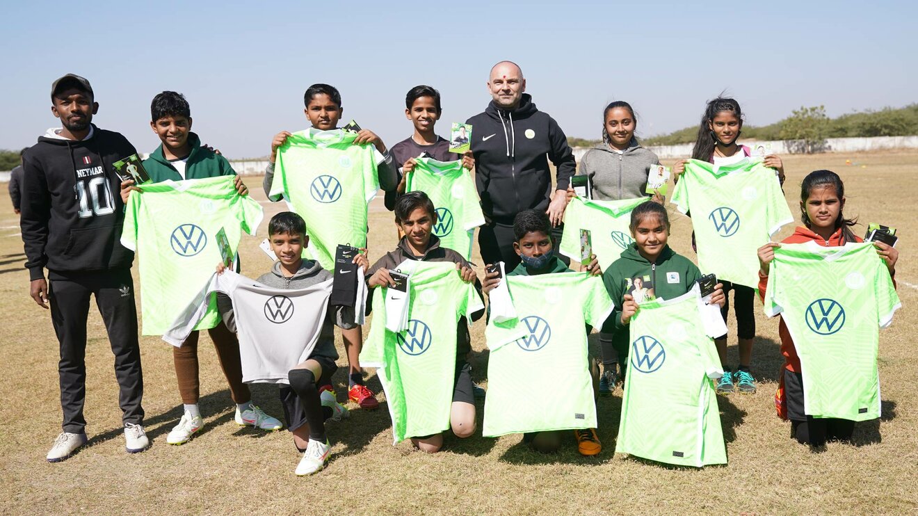 Ein Gruppenbild mit Dirk Zelonczewski und Kindern die VfL Wolfsburg-Trikots in den Händen halten.