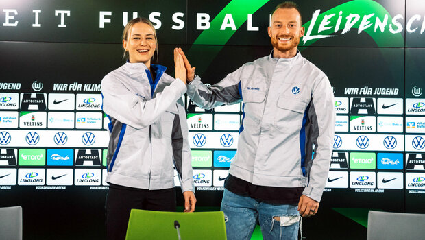 Die VfL-Wolfsburg-Spielerin Merle Frohms und Maximilian Arnold klatschen sich in den Volkswagen-Arbeitsjacken ab.