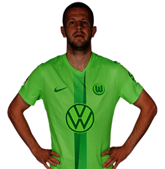 Der VfL Wolfsburg Spieler Denis Vavro mit den Händen in der Hüfte.