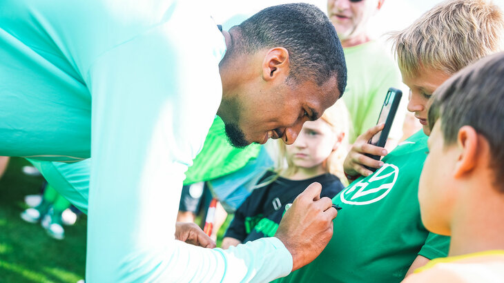 Der VfL-Wolfsburg-Spieler Moritz Jenz unterschreibt einem Jungen sein Tshirt.