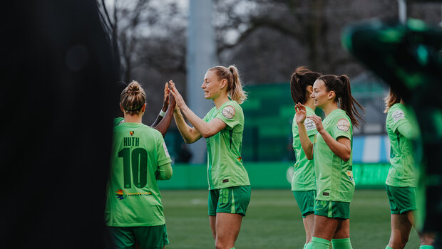Die Spielerinnen der VfL-Wolfsburg-Frauen stehen in der AOK-Arena und klatschen sich gegenseitig in die Hände.