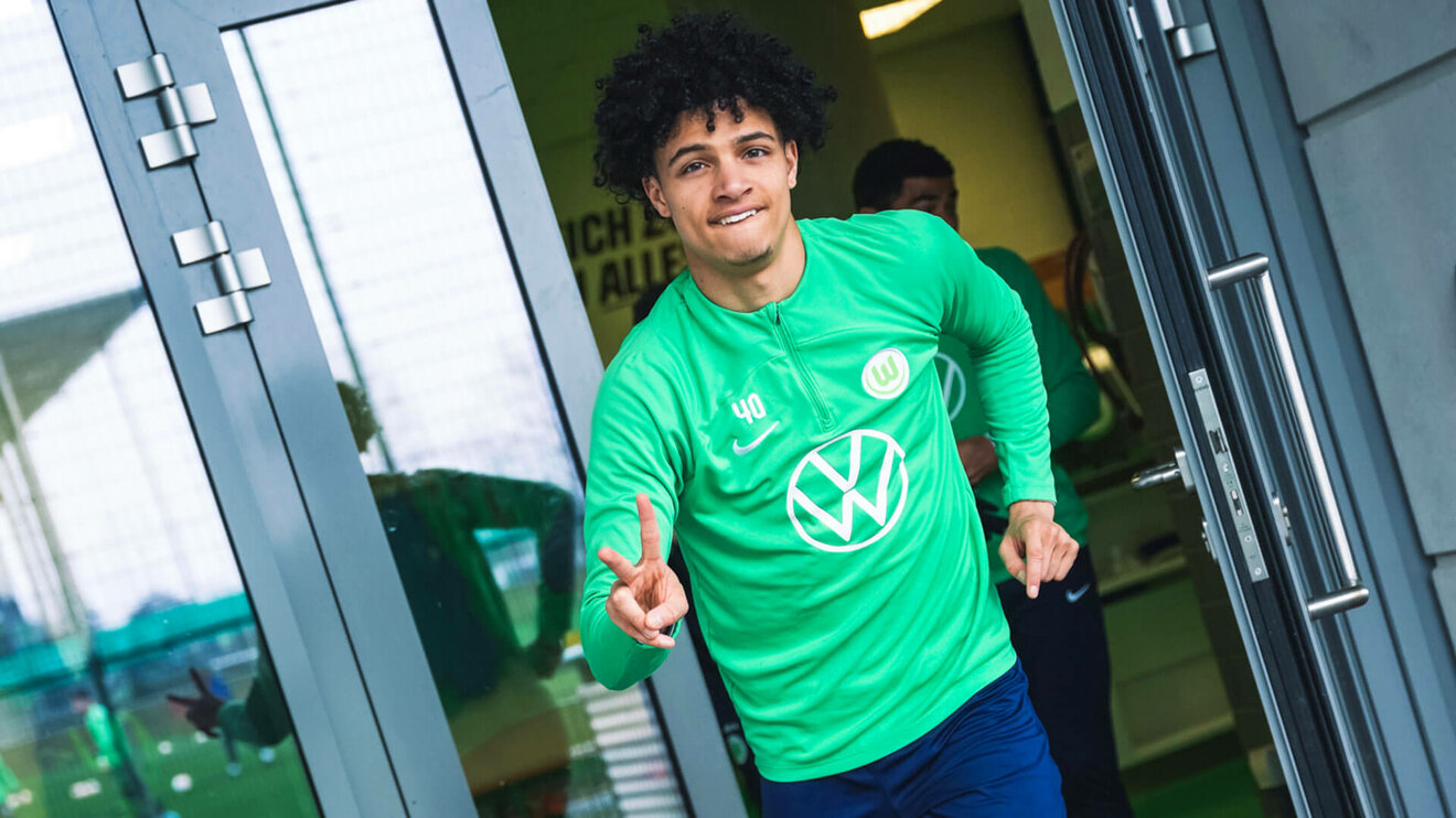 Der VfL Wolfsburg-Spieler Kevin Paredes schaut lachend in die Kamera.