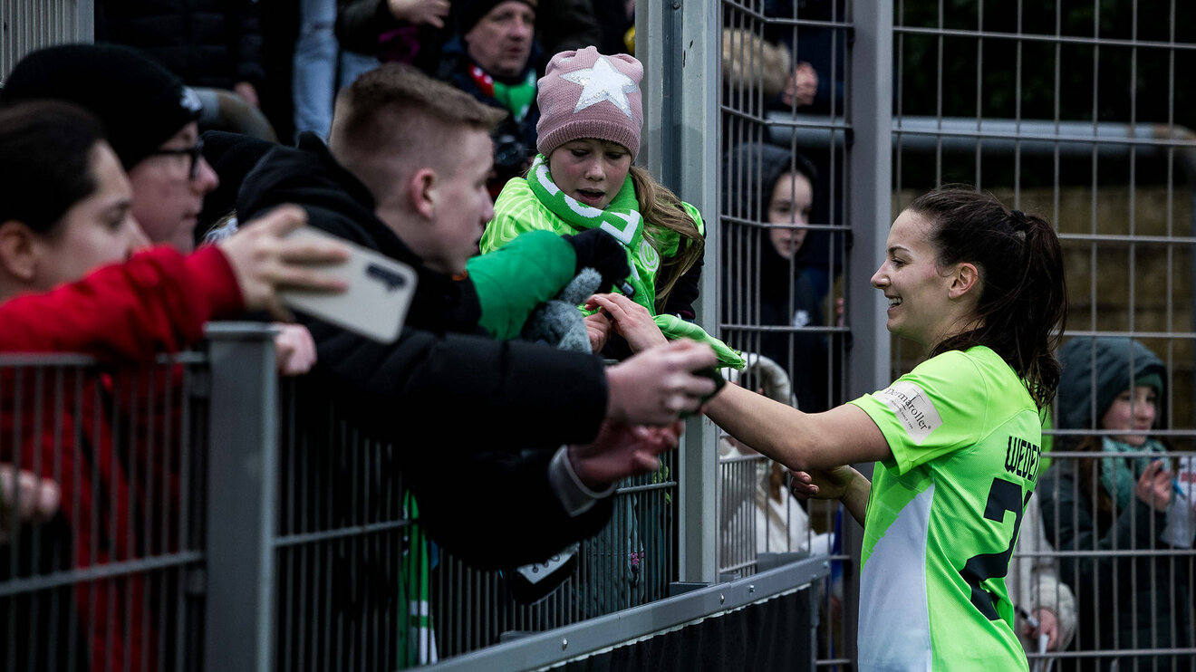 VfL-Wolfsburg-Spielerin Joelle Wedemeyer gibt einem Fan nach dem Spiel ein Autogramm.