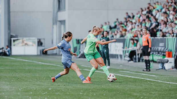 Ella Peddemors vom VfL Wolfsburg ist mit dem rechten Fuß am Ball. Hinter ihr wird sie von einer Gegenspielerin verfolgt. 