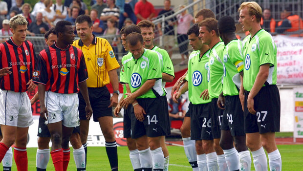 VfL Wolfsburg Spieler bilden eine Mauer vor dem Tor, vor ihnen stehe einige Spieler aus Freiburg.