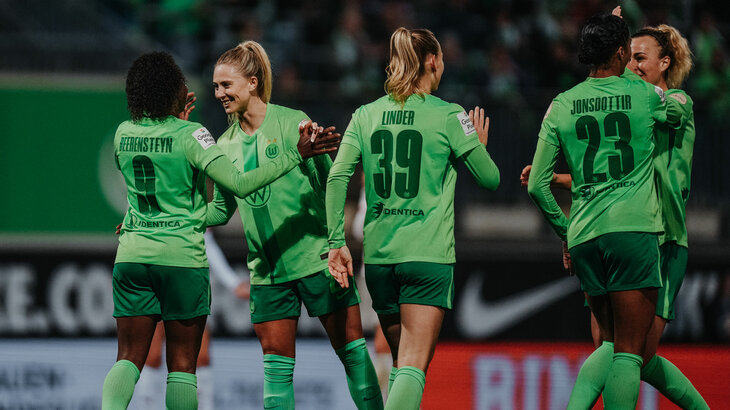 Spielerinnen des VfL Wolfsburg stehen im Stadion und klatschen sich gegenseitig in die Hände.