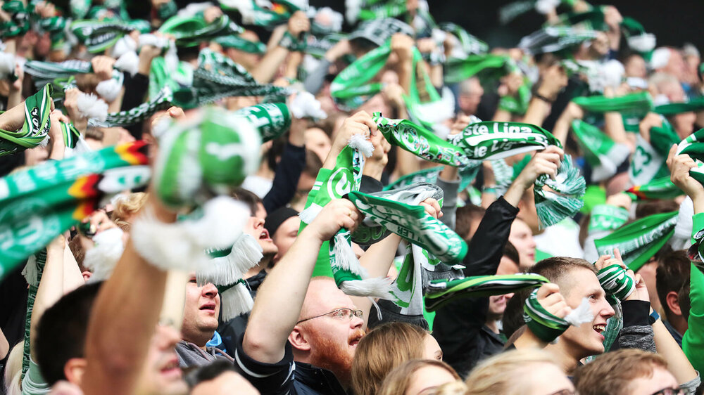 VfL-Wolfsburg-Fans wedeln mit ihren Schals.