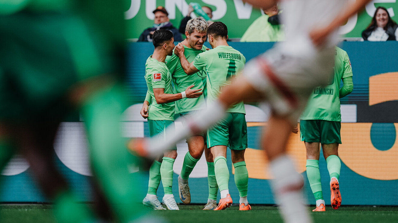 Die VfL-Wolfsburg-Spieler Mohammed Amoura, Jonas Wind und Konstantinos Koulierakis jubeln gemeinsam.