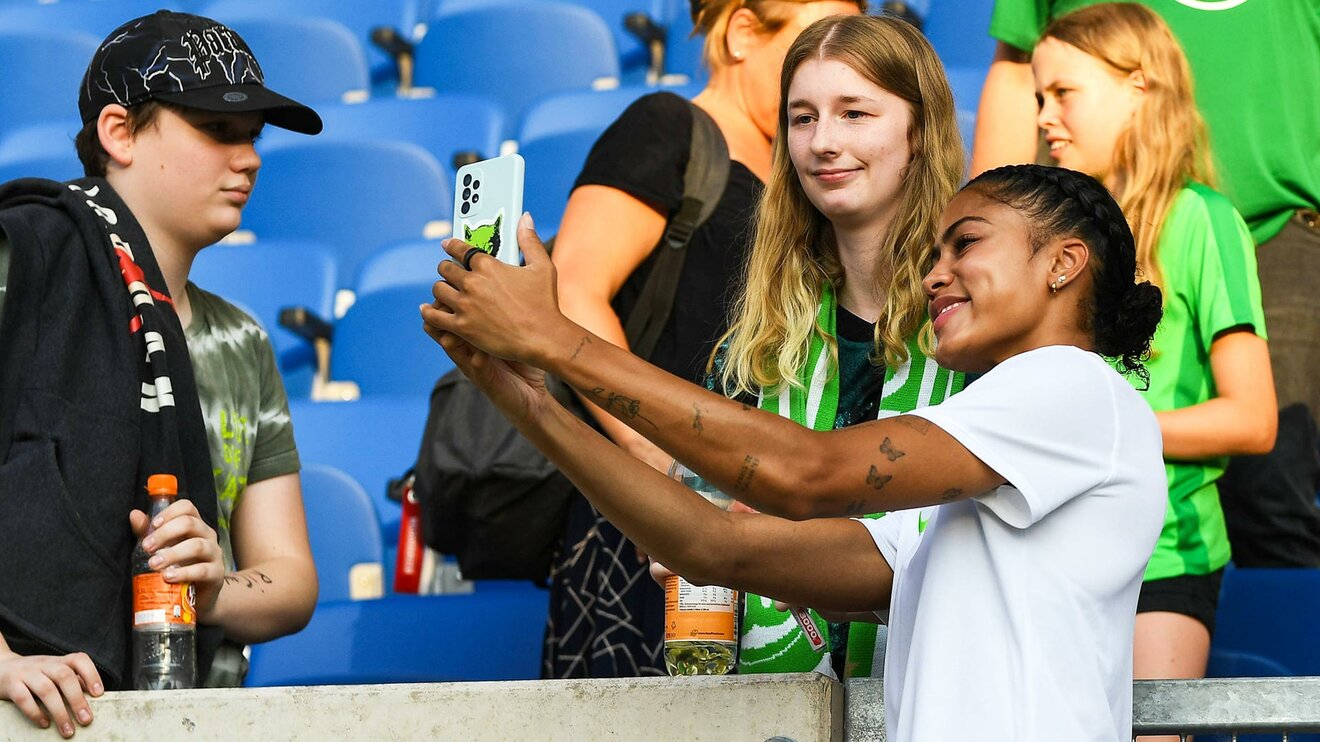 Sveindis Jonsdottir, Spielerin des VfL Wolfsburg, macht nach dem Training ein Bild mit einem Fan.