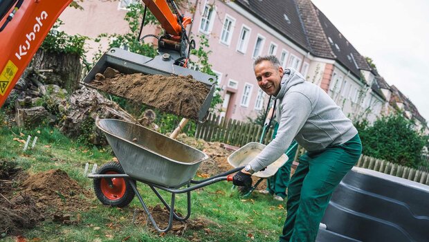 VfL Wolfsburg Mitarbeiter mit Schubkarre und Latzhose am "Wir-für euch"-Tag.