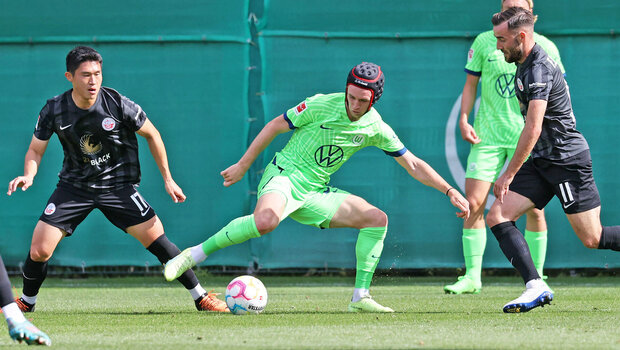 VfL-Wolfsburg-Spieler Patrick Wimmer klärt sich den Ball zwischen den Gegnern aus Rostock. 