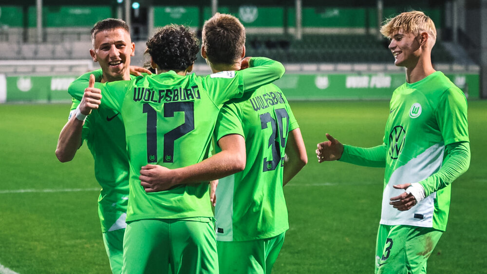 Vier Spieler der U19-Mannschaft des VfL Wolfsburg stehen jubelnd beisammen.