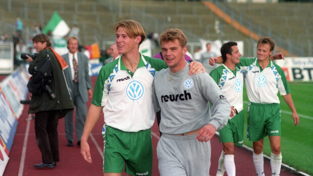 Ehemalige Spieler des VfL Wolfsburg umarmen sich.