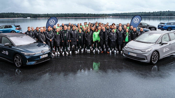 Die Spielerinnen und Spieler des VfL Wolfsburg posieren mit zwei ID.3 für ein Gruppenbild im Rahmen eines Fahricherheitstrainings.