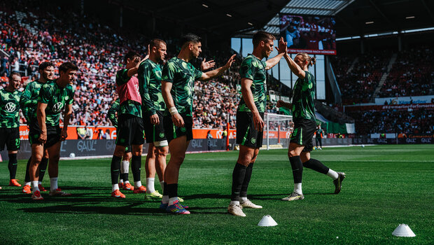 Die VfL-Wolfsburg-Spieler klatschen sich beim warm machen ab.