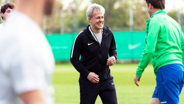 Pierre Littbarski lacht mit Spielern aus der Traditionsmannschaft des VfL Wolfsburg.