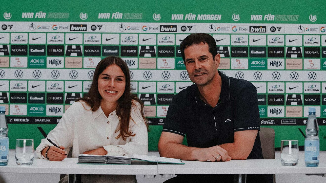 VfL-Wolfsburg-Spielerin Maja Zielinska unterschreibt ihren Vertrag. Neben ihr sitzt Ralf Kellermann.