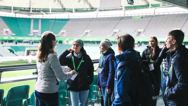 Die Teilnehmenden am VfL-Wolfsburg-Zukunftstag stehen im Stadion.